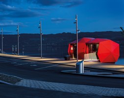 Badar i ljus! De glansiga Ferrari-röda fasadskivorna skapar ett spännande uttryck under mörka nätter vid Mjøsa.                              Foto: Tomasz Majewski